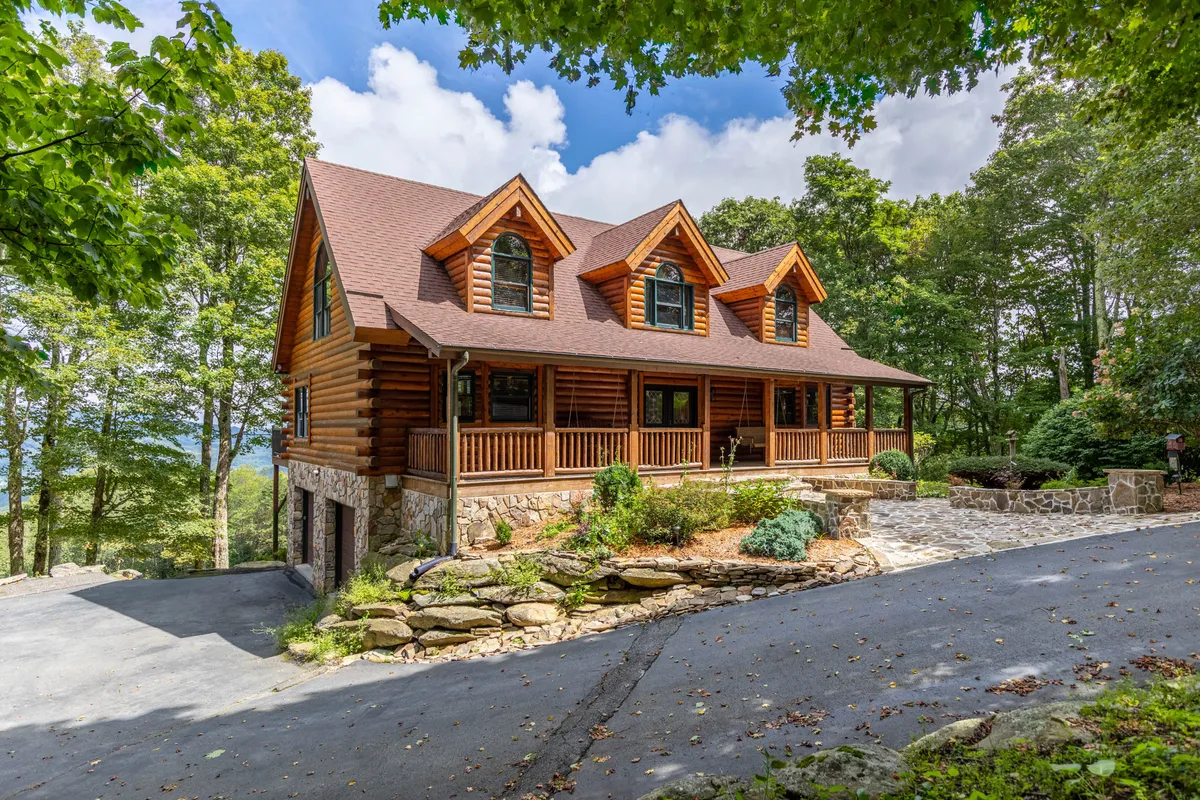 A cozy log cabin with a welcoming wooden porch, stone pathway, and lush greenery. The setting feels tranquil and inviting, highlighting the retreat's natural privacy and access to outdoor areas for activities or quiet reflection.